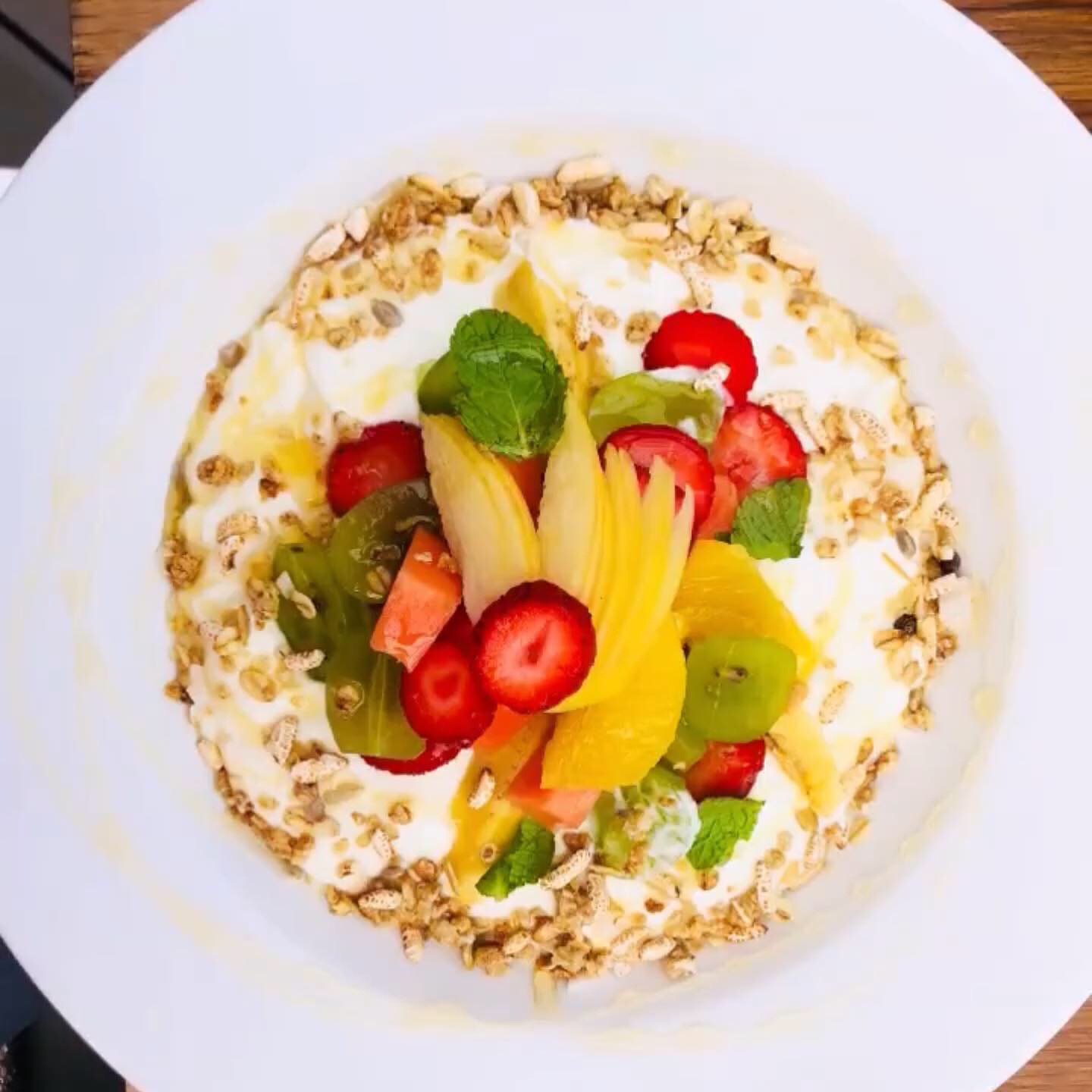 Yoghurt bowl with granola, mango, strawberry and mint