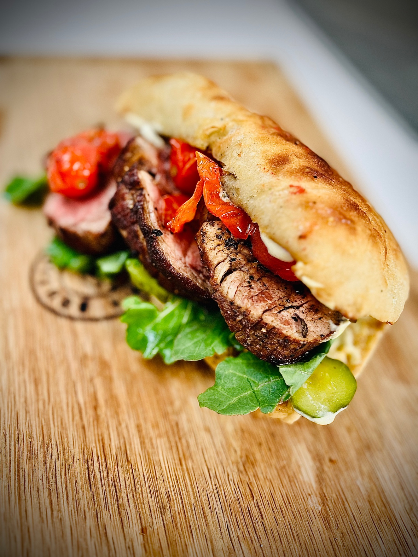 Rare beef fillet sandwich with roasted tomato on ciabatta