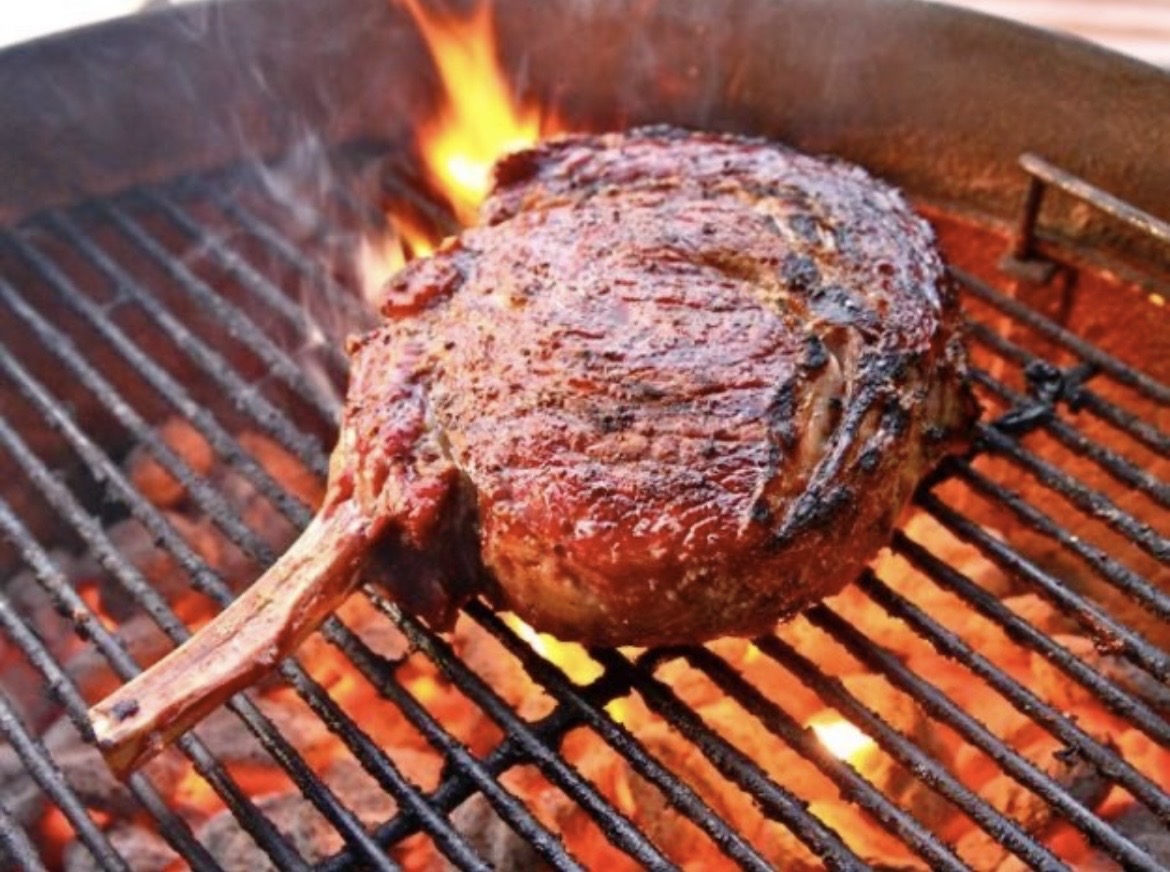 Tomahawk steak flame-grilled over open coals