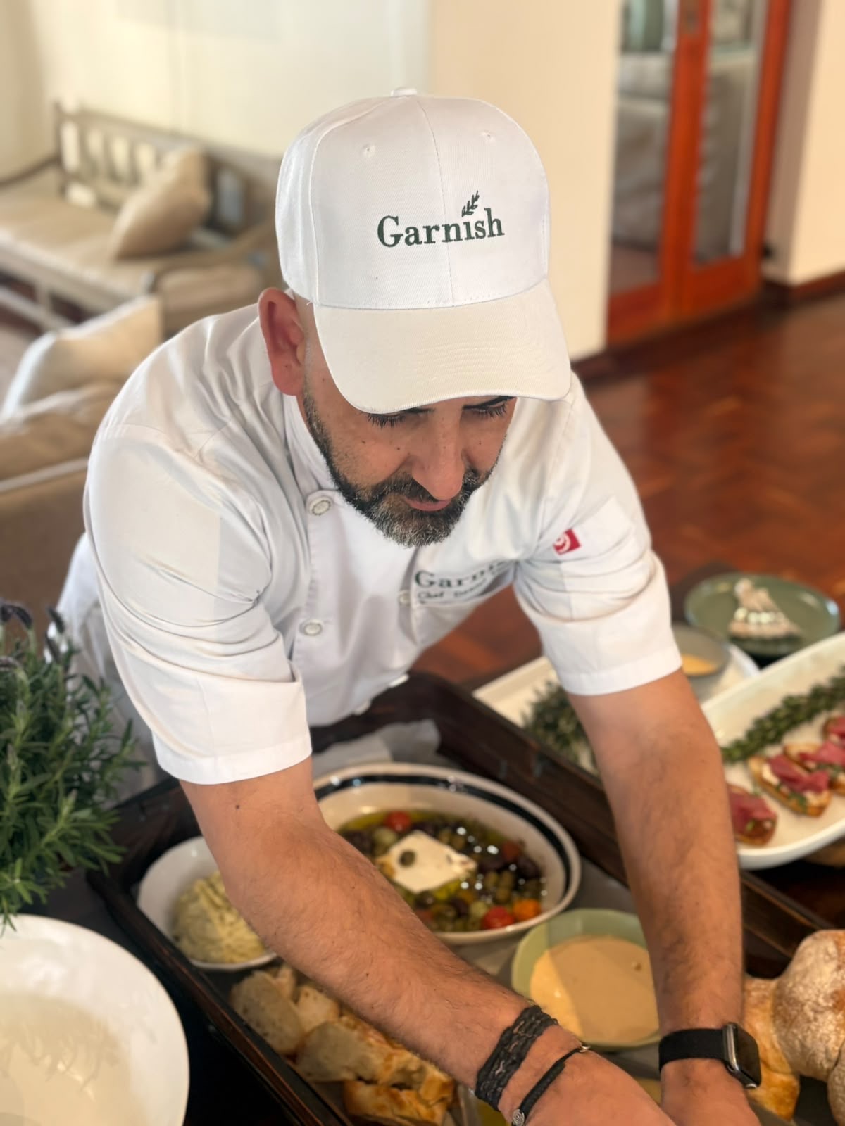Chef Daniel Vieira plating a mezze spread in a Garnish chef jacket and cap